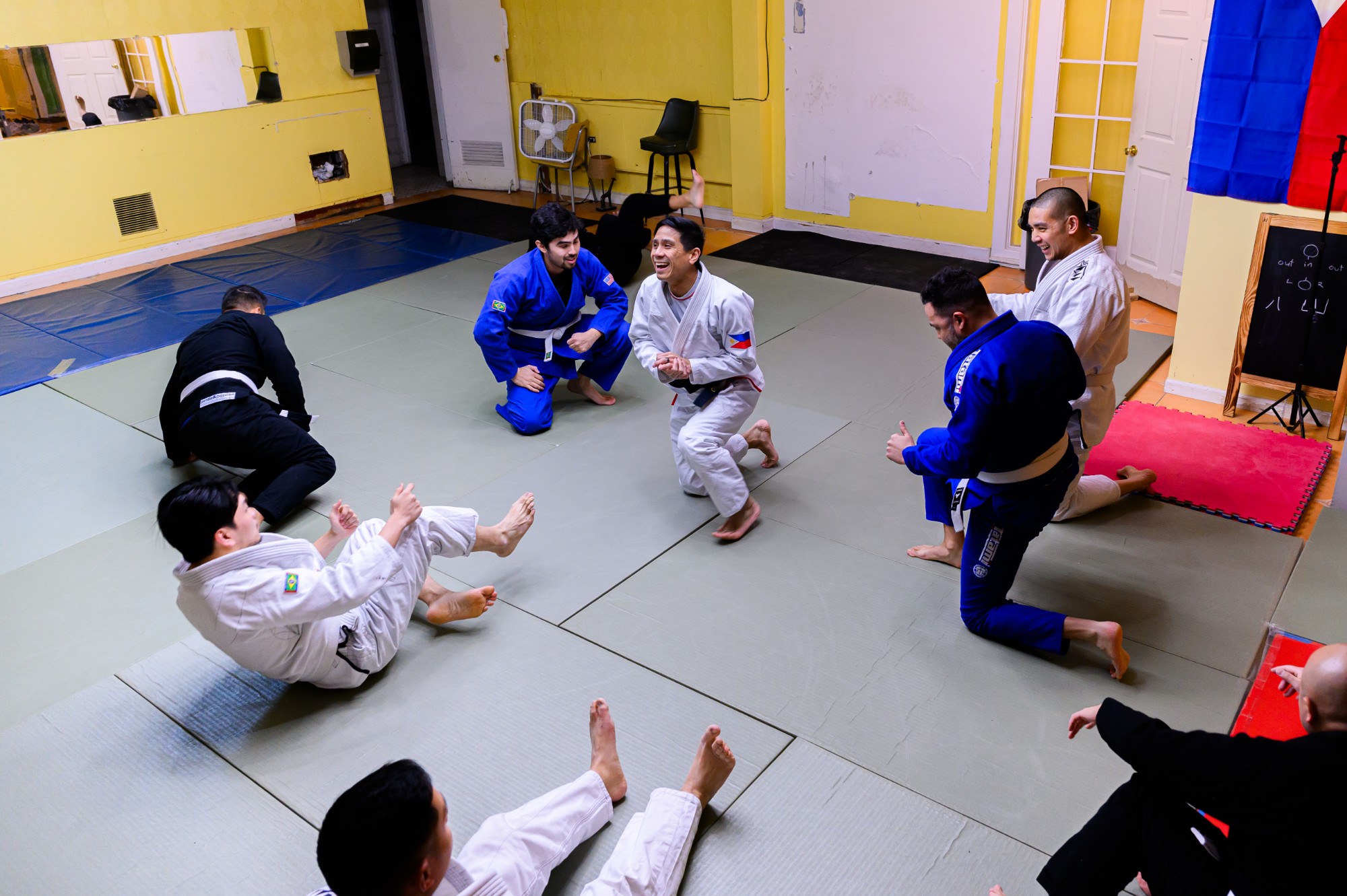 Students and coaches laughing together on the mat mid-class at Project Clarito's Chicago academy.