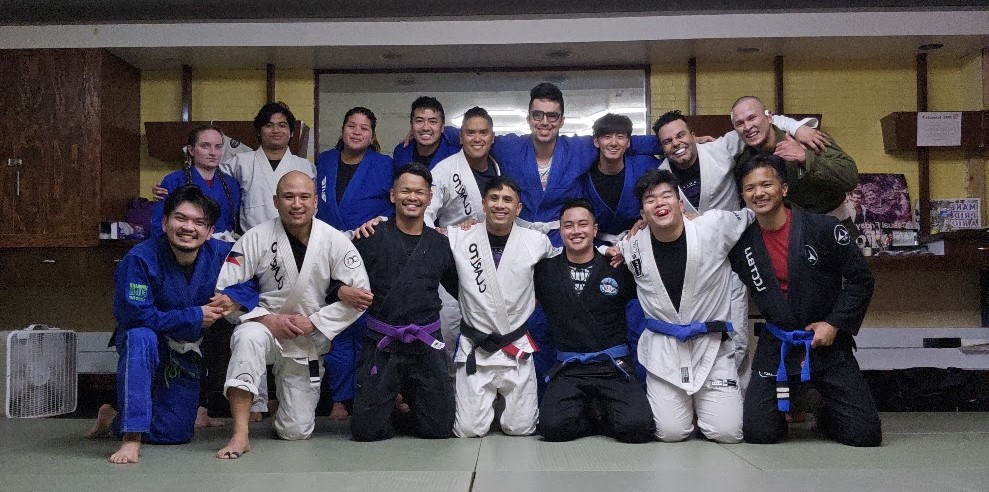 The Project Clarito group at the Rizal Center in Chicago — students and coaches of every belt level, arms around each other, smiling after class.